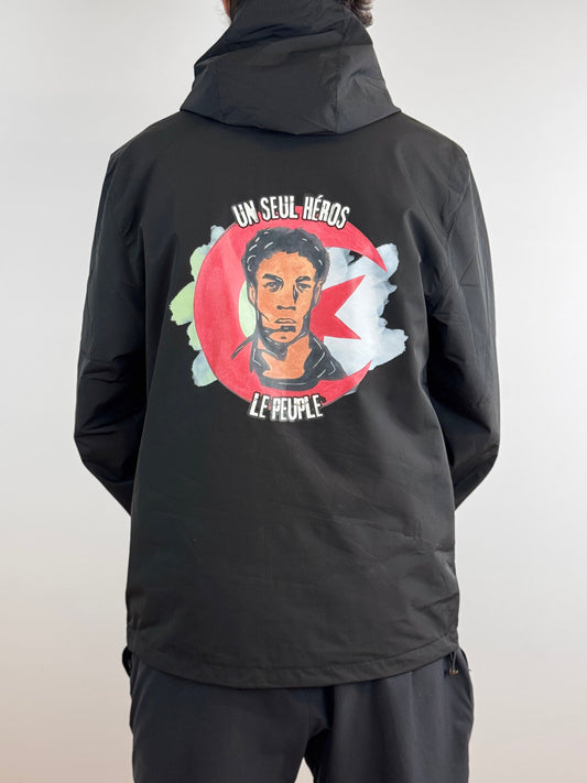 veste imperméable un seul héros le peuple par lacasbah paris, vue de dos avec comme design le visage d'ali la pointe accompagné d'un nuage qui rappelle le drapeau algérien